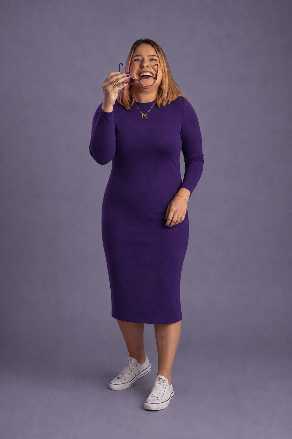 Priscilla Cruz em pé, de vestido roxo, corpo inteiro